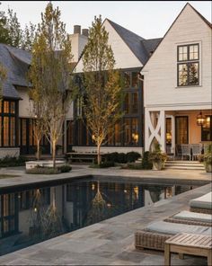 a house with a pool in front of it and trees around the pool area on either side