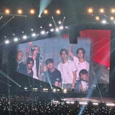 a group of young men standing on top of a stage with their hands in the air