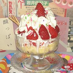 an ice cream sundae with strawberries and whipped cream in a glass dish on a plate