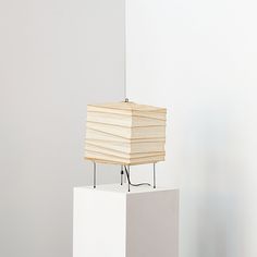 a sculpture made out of wood on top of a white block in the middle of a room