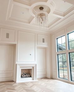 an empty room with a fireplace and large windows