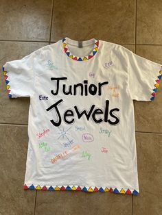 a white t - shirt with the words junior jewels written in multicolored letters