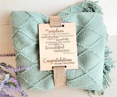 a blue blanket with a wooden plaque on it and some lavenders in the background