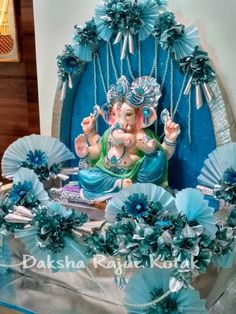 an elephant statue sitting on top of a table with blue flowers and decorations around it