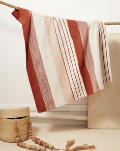 a red and white striped towel hanging on a rope next to a basket with tassels