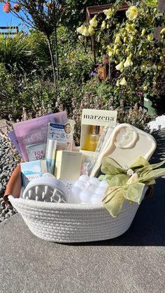 a white basket filled with lots of items on top of a cement ground next to flowers