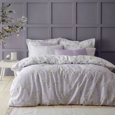 a bed with white and purple comforters in front of a wooden paneled wall