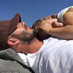 a man laying on top of a woman's back while she kisses her forehead