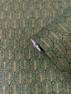 a pair of scissors sitting on top of a green and gold patterned table cloth,