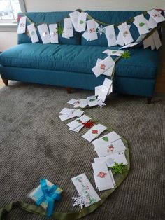 a blue couch sitting in a living room next to a window covered in paper snowflakes