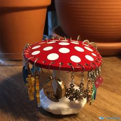 a red mushroom with white polka dots on it sitting on a table next to potted plants