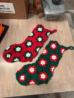 two crocheted christmas stockings sitting on top of a wooden table next to each other