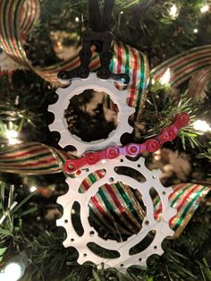 an ornament hanging from a christmas tree with colorful ribbons and bicycle gear on it