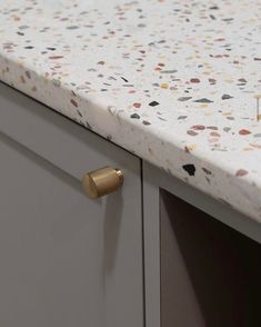 a white counter top with gold knobs on it's side and an open drawer in the middle