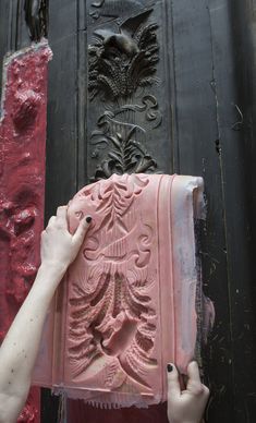 a woman is painting the front door of a building with red paint and black trim