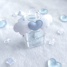 a small glass bottle with a heart on it sitting on a white surface surrounded by crystal stones