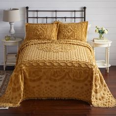 a bed with yellow bedspread and matching pillows