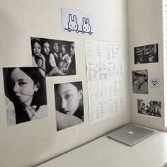 a laptop computer sitting on top of a white desk in front of a wall covered with pictures