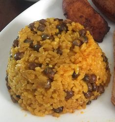 a white plate topped with rice and beans next to two pieces of bread on a table