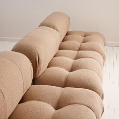 a long couch sitting on top of a hard wood floor next to a white wall