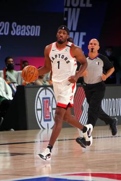 a basketball player dribbles the ball while being guarded by an official