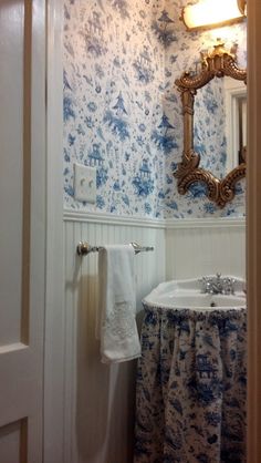 a bathroom with blue and white wallpaper and a sink in the corner next to a mirror