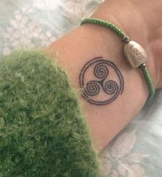 a woman's arm with a tattoo on it and a green bracelet around her wrist