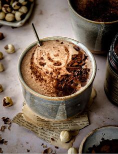 two cups filled with hot chocolate on top of a table next to nuts and spoons