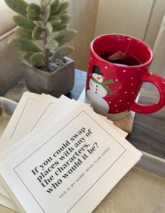 a cup of tea next to some cards and a potted plant