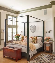 a bedroom with a four post bed and rugs on the wooden flooring in front of it