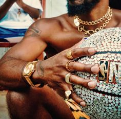 a man with gold rings on his hands holding a large ball in front of him