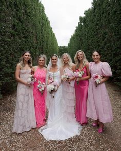 a group of women standing next to each other in front of some bushes and trees