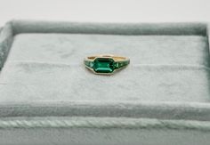 At the centerpiece of this lab grown Zambian emerald ring is a radiant 1.5 ct emerald, set east west to highlight its natural allure. Flanking it are calibre cut emeralds, each uniquely shaped to create a seamless gradient effect, making every ring truly one-of-a-kind. Set in luxurious 18K yellow gold, this ring exudes timeless charm. What makes it truly special? Calibre cut stones are individually shaped to fit precisely into the design, resulting in a mesmerizing display of color and brillianc Timeless Asscher Cut Green Emerald Ring, Timeless Emerald Ring With Radiant Cut, Timeless Baguette Cut Green Emerald Ring, Timeless Green Baguette Cut Emerald Ring, Timeless Green Baguette-cut Emerald Ring, Heirloom Emerald Ring Baguette Cut, Timeless Baguette Cut Emerald Ring Gift, Heirloom Baguette Cut Emerald Ring, Heirloom Style Baguette Cut Emerald Ring