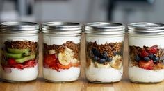 four mason jars filled with granola and fruit