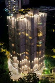 an aerial view of a tall building with lights on it's sides at night