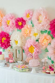 a table topped with lots of desserts and flowers on top of a white table cloth