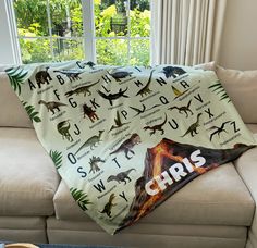 a couch with a blanket that has dinosaurs on it and the words'abcr is