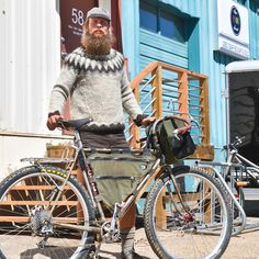 a bearded man standing next to his bike