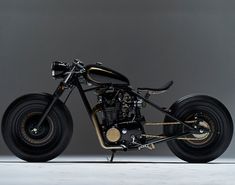 a black and gold motorcycle parked on top of a white floor next to a gray wall