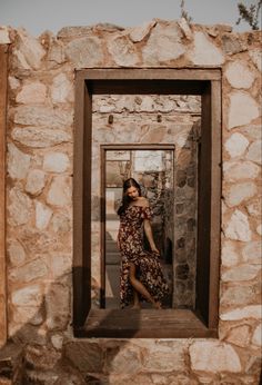 a woman standing in an open window on a stone wall