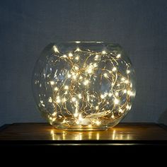 a glass vase filled with lights on top of a wooden table