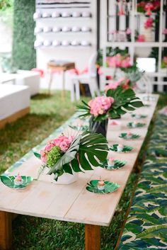 the table is set up with pink flowers and green leaves on it for a party