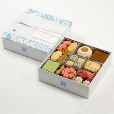 a box filled with lots of different types of food next to a white table top