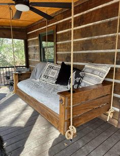 a wooden bed sitting on top of a porch next to a ceiling fan and windows