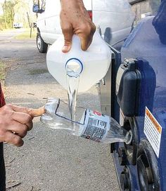 a man is filling up a plastic bottle with water from a gas pump into his truck