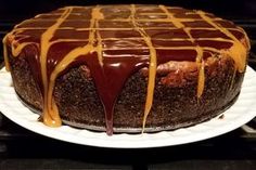 a chocolate cake with caramel drizzle on top sitting on a white plate