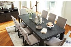 a dining room table and chairs in front of a window with white flowers on it