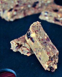 two pieces of granola bar sitting on top of a black surface next to a spoon