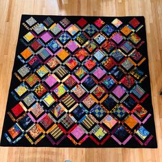 a person standing next to a quilt on the floor with their feet propped up in front of it