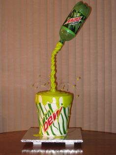 a green and white cup sitting on top of a table next to a soda bottle